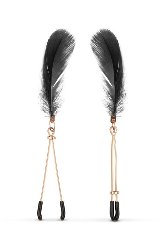 Les pinces tétons couleur rose gold avec embouts en plastique noir, et des plumes noires, comprises dans le kit BDSM