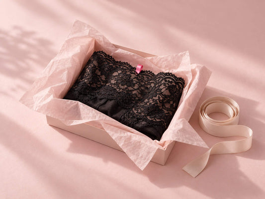 Dentelle noire dans un papier de soie rose et mètre ruban, pour choisir sa lingerie sexy