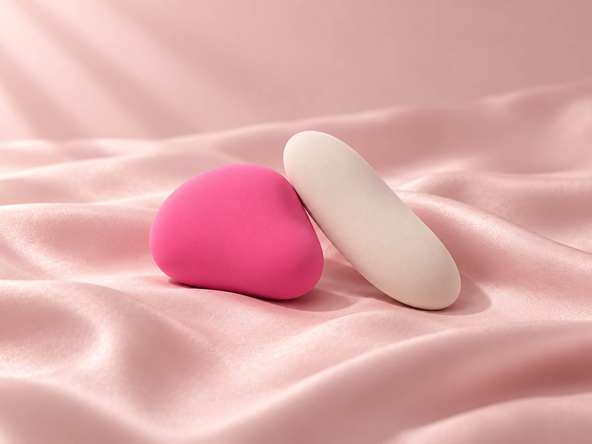 Deux objets aux formes douces, l'un compact, l'autre allongé, pour comparer stimulateur clitoridien et vibromasseur