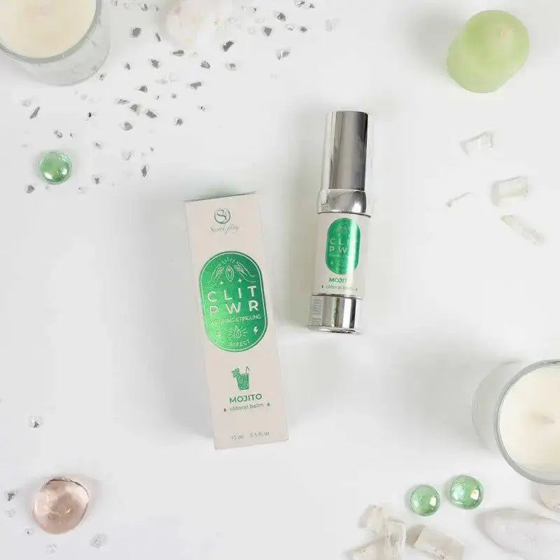 Baume clitoris Clit Pwr Mojito de Secret Play sur une surface lumineuse, entouré de décorations scintillantes.