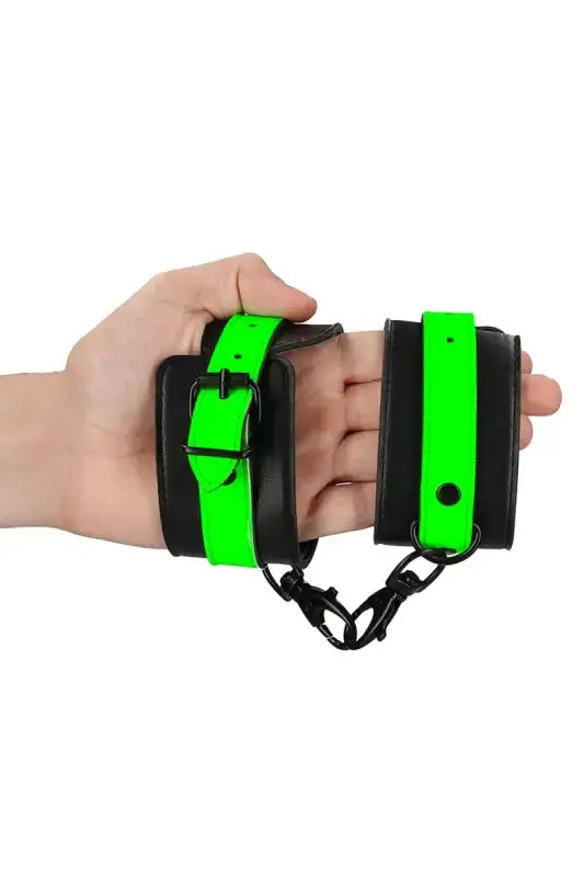 Menottes phosphorescentes de chevilles Ouch! dans une main, conçues pour des jeux coquins lumineux
