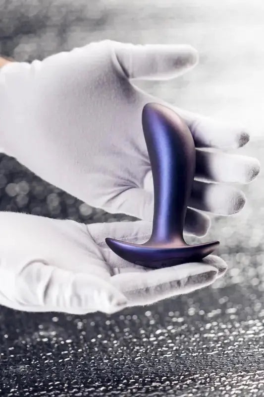Plug vibrant Uranus de Hueman présenté dans une main avec des gants, mettant en avant son design élégant.