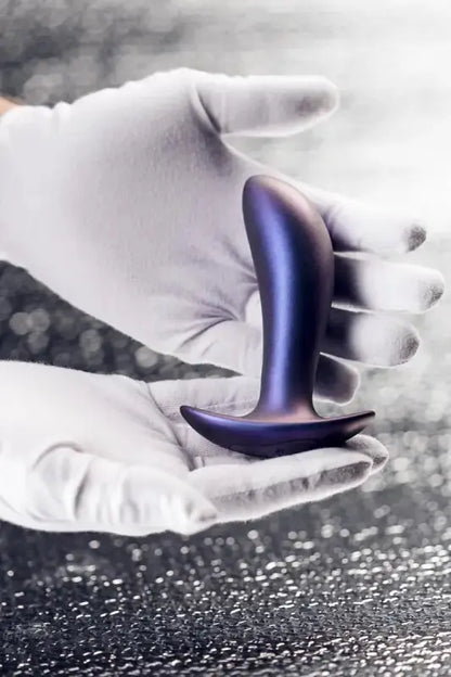 Plug vibrant Uranus de Hueman présenté dans une main avec des gants, mettant en avant son design élégant.