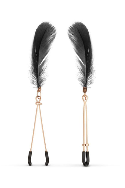 Les pinces tétons couleur rose gold avec embouts en plastique noir, et des plumes noires, comprises dans le kit BDSM 
